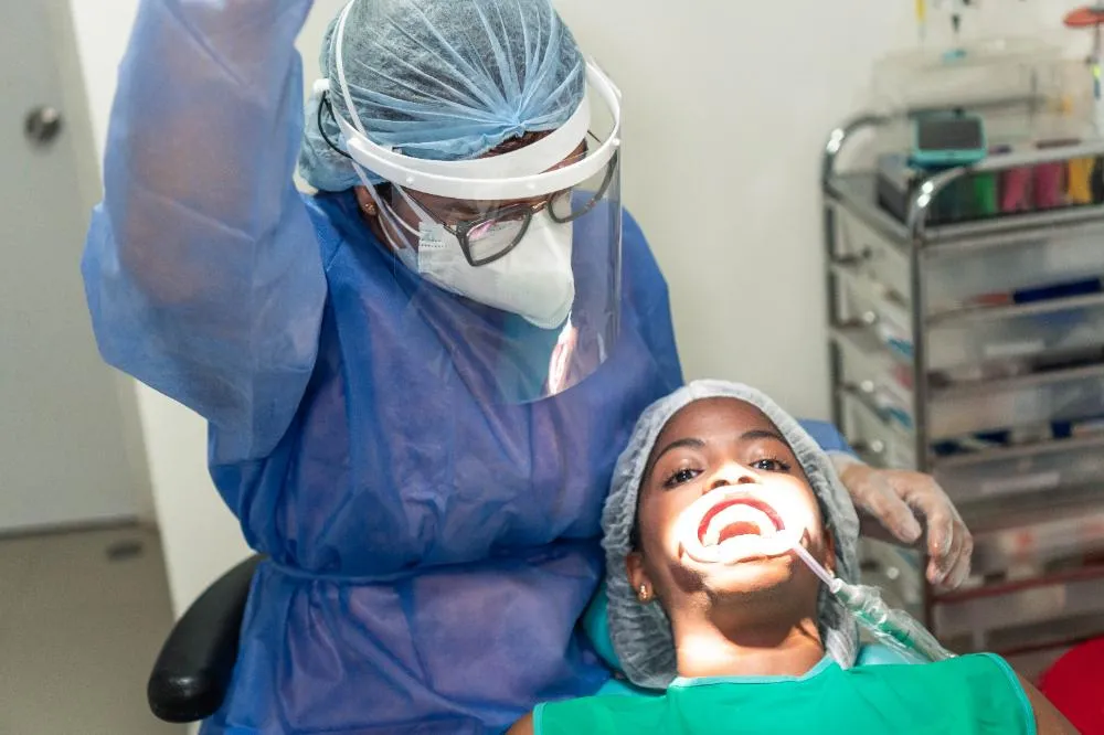 Dentist Wearing Ppe Performing Checkup On Young Patient